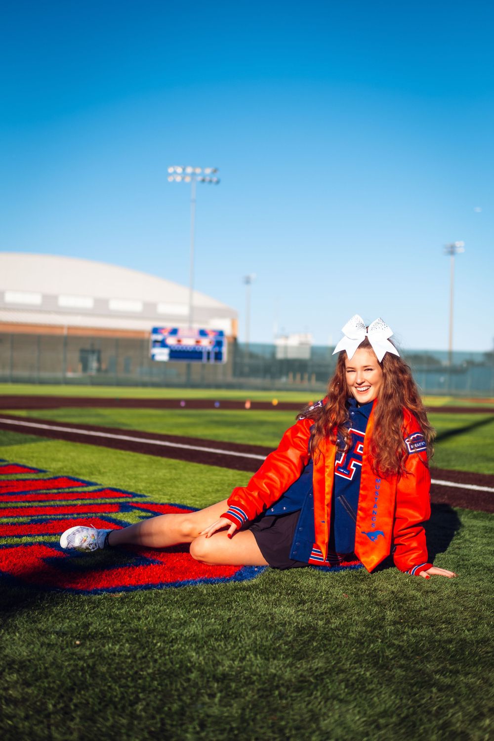Sports-themed portrait on football field with stadium lights in background.