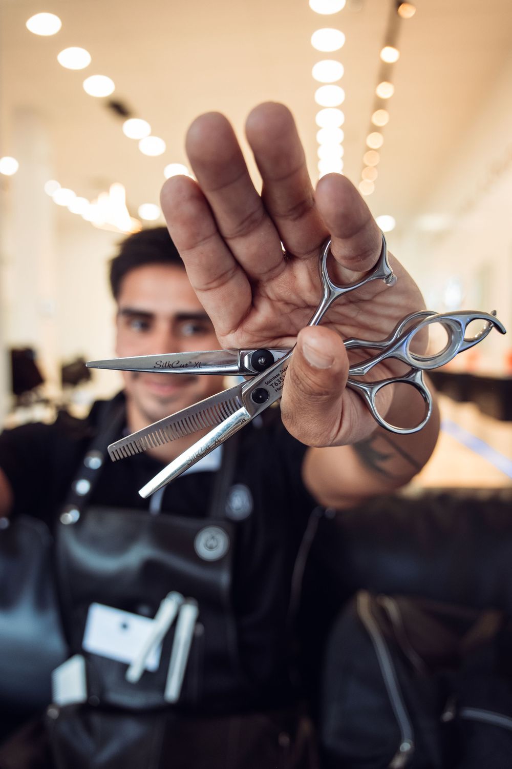 Professional hairdressing scissors held up against blurred salon background.