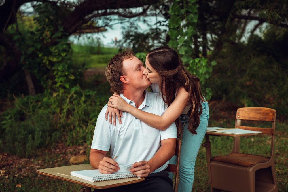 Romantic outdoor moment captured between couple at vintage wooden desk.