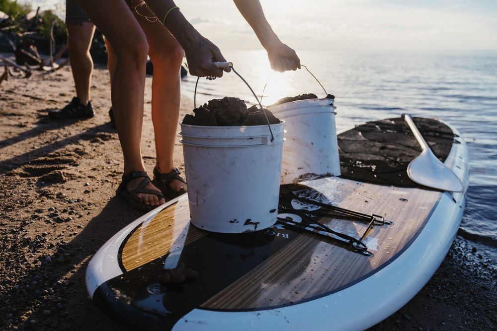 White buckets rest on a paddleboard by the ocean shore during a beach outing at sunset.