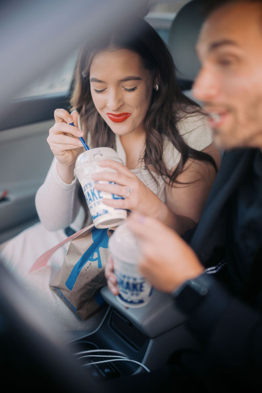 Two people enjoying milkshakes from Sonic Drive-In while sitting in a car.