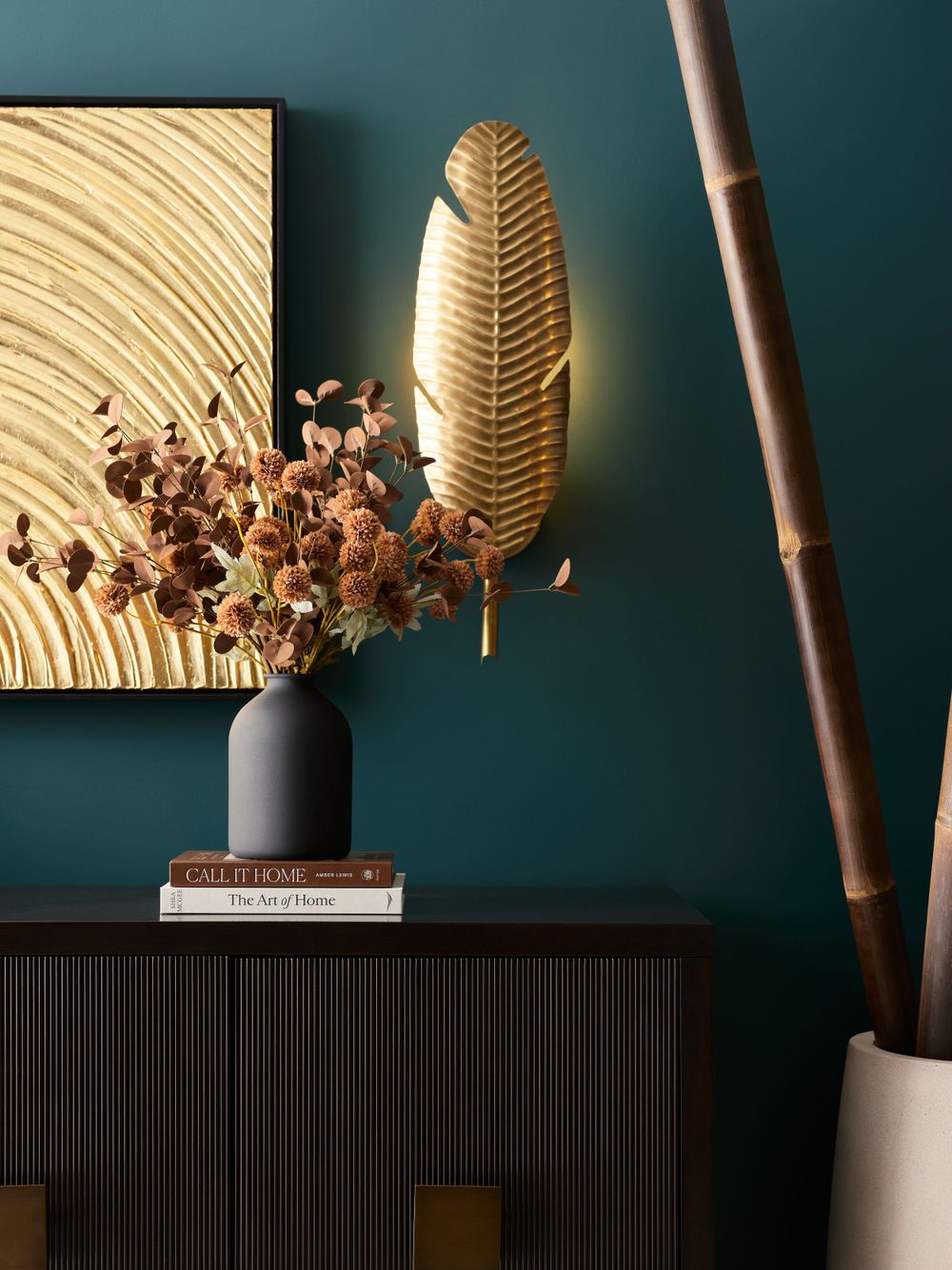 Bold vignette with teal accent wall, sculptural wall sconce, and natural dried florals — creative interior moment by Khoi Ly Photography.
