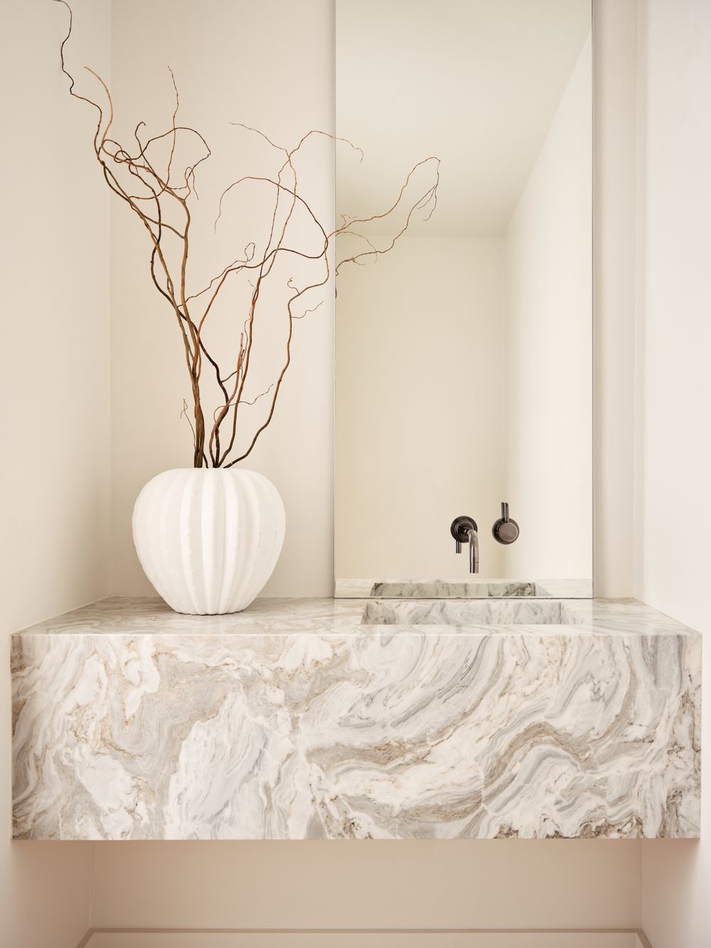 Elegant powder room with sculptural marble vanity and tall white vase centerpiece — interior styling by Khoi Ly.