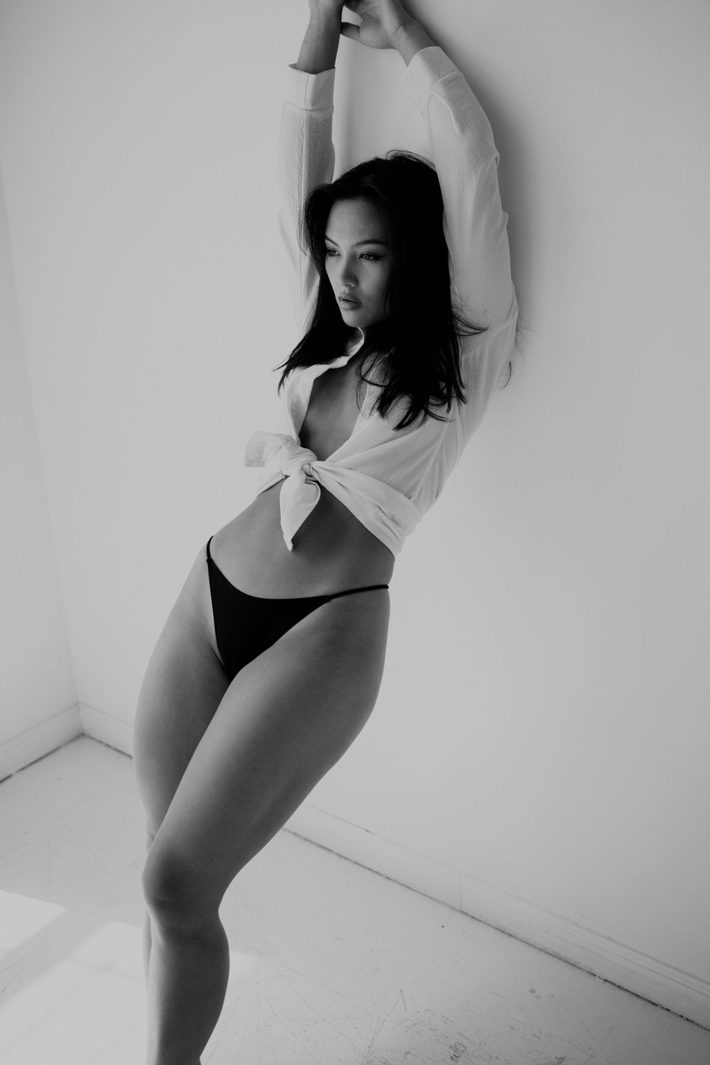 Artistic black and white dance photography sequence showing movement against a white wall.