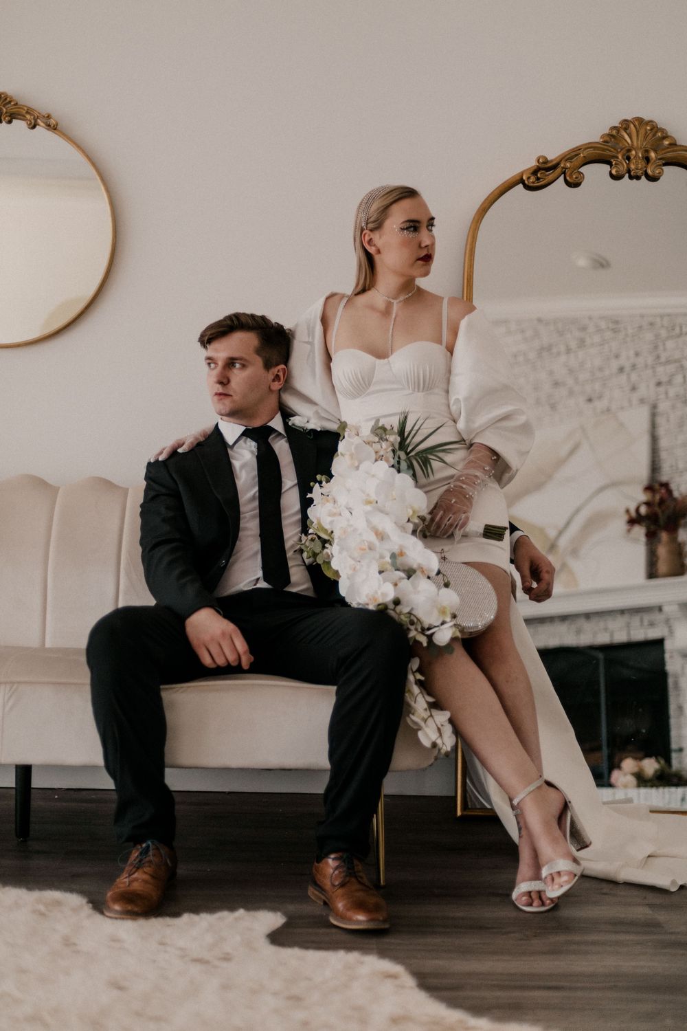 Wedding couple's feet and formal attire shown while sitting on vintage furniture.
