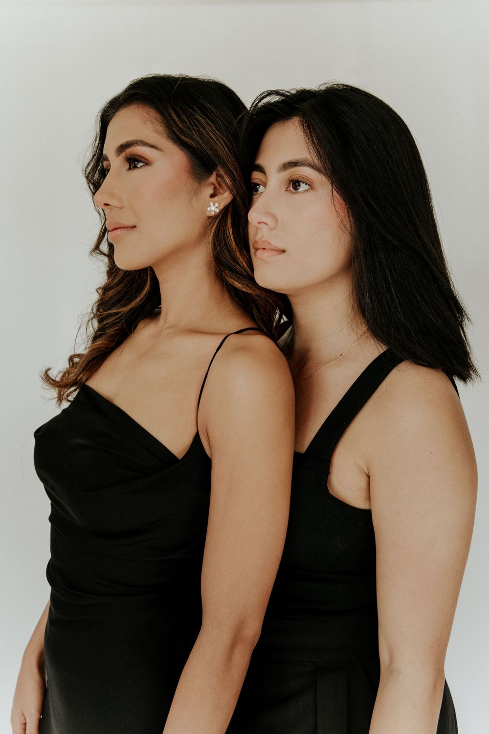 Studio portrait series featuring two models in black dresses against a white background.