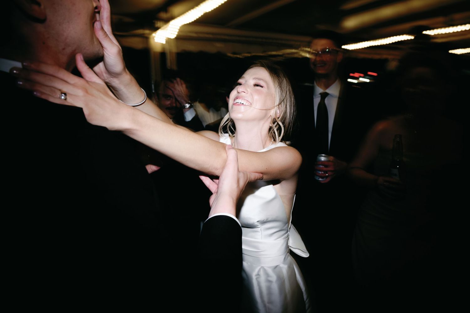 A candid moment of joyful dancing at a dimly lit wedding reception.