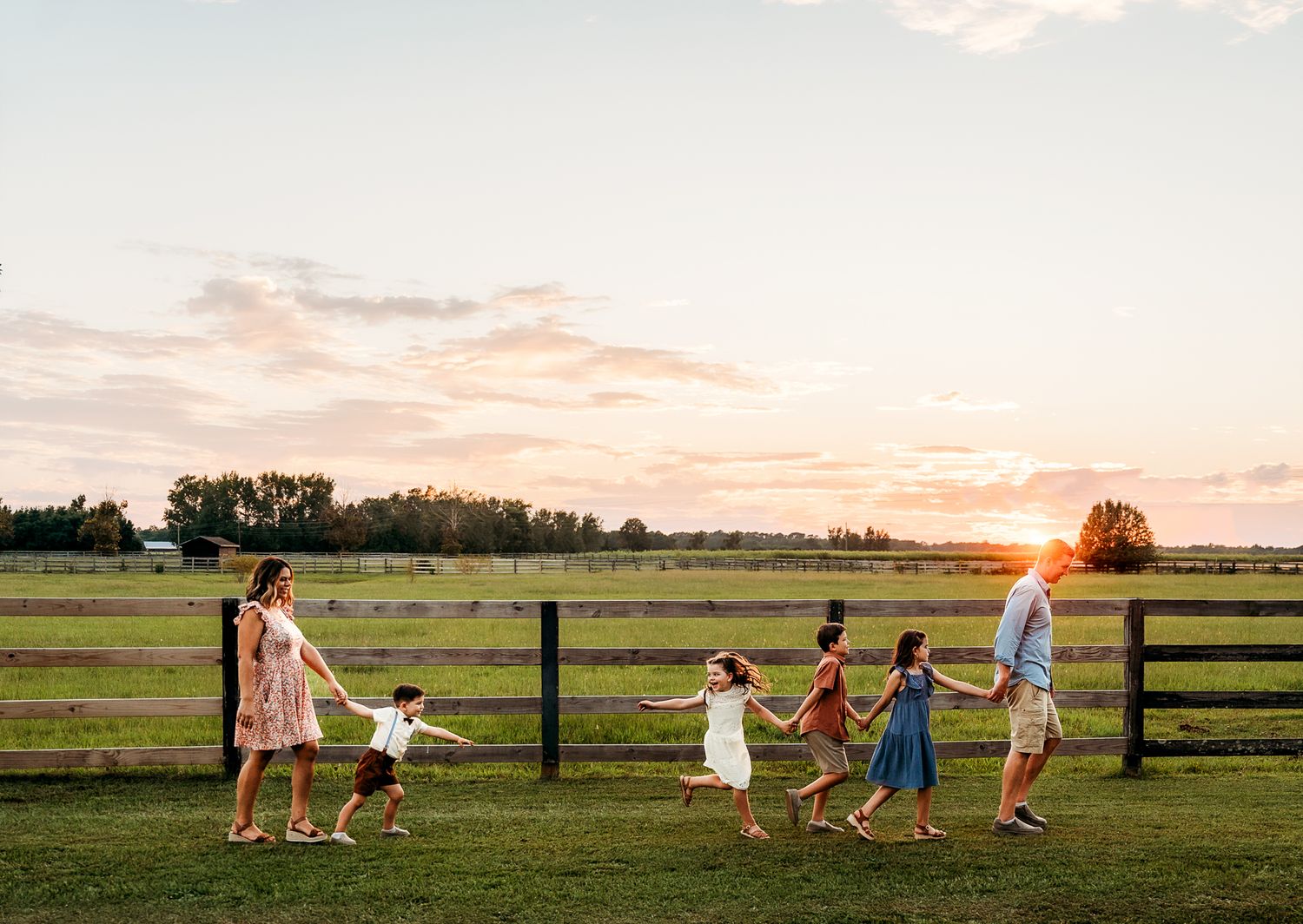 Family walking together along fence line during sunset in countryside roscoe IL photographer