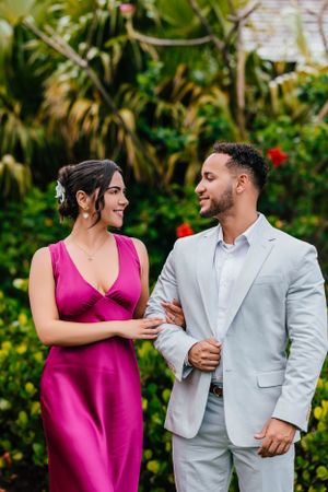 A couple in elegant attire sharing a romantic moment in a lush garden setting.