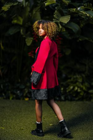 Urban fashion ensemble featuring red blazer, shorts and boots against green backdrop.