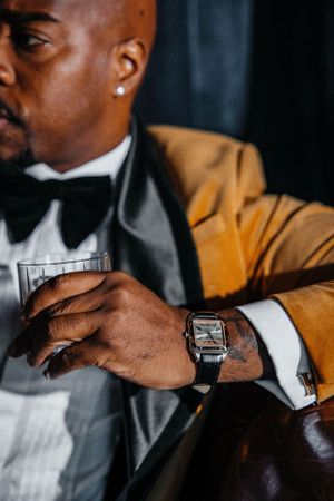 Close-up of hand holding glass wearing formal attire and silver watch.