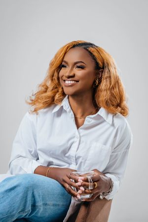 A cheerful portrait featuring someone in casual business attire against a neutral gray backdrop.