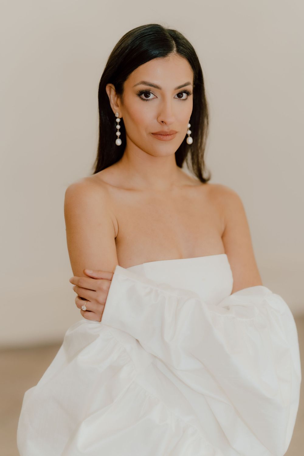 Elegant bridal portrait featuring strapless white gown and dangling pearl earrings.