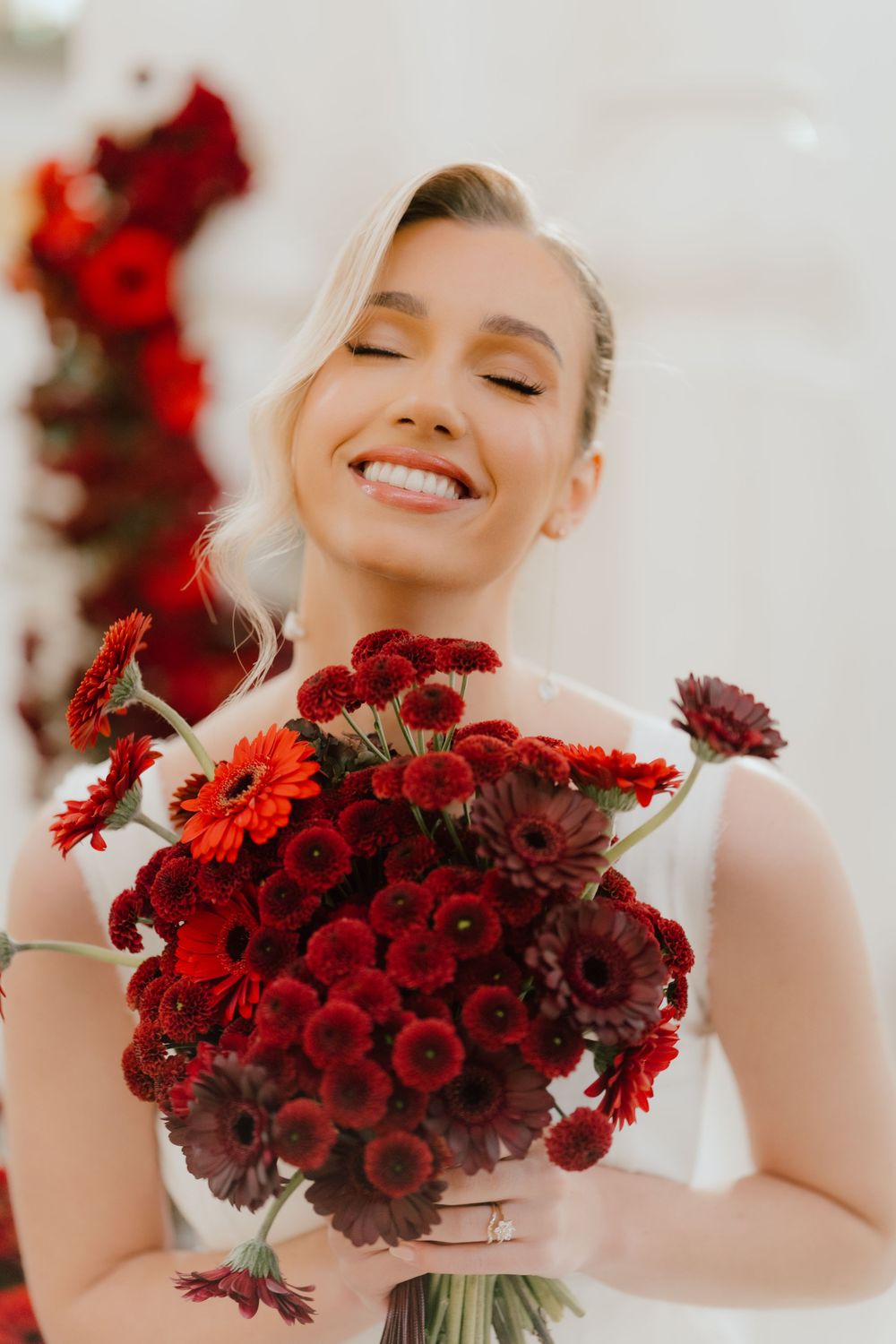 Person holding vibrant red bouquet of flowers while smiling joyfully.
