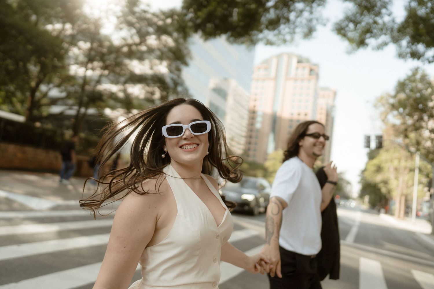 Wedding party walking and laughing together on a sunny sidewalk.