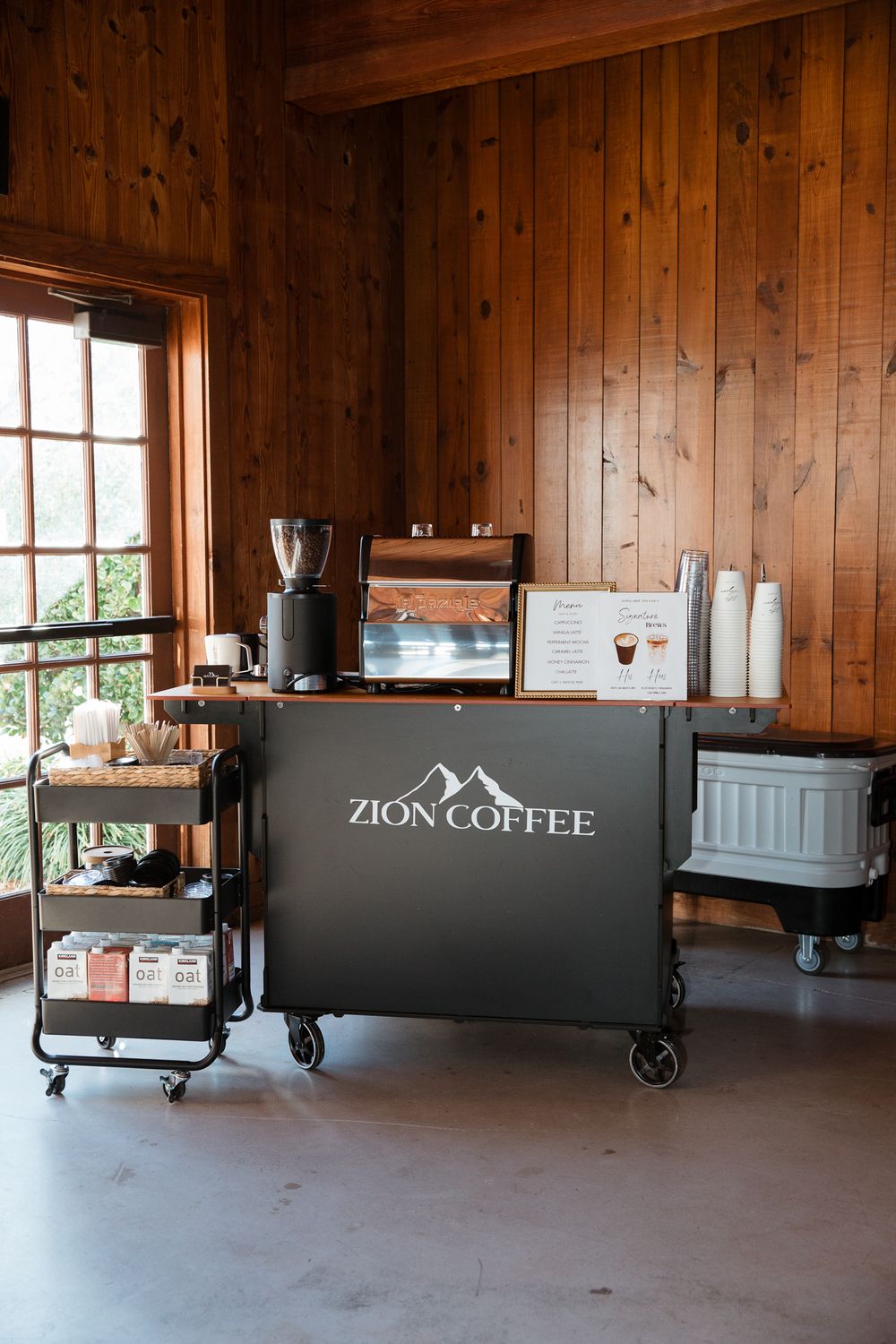 Mobile coffee bar setup with Zion Coffee equipment in a wooden paneled room.