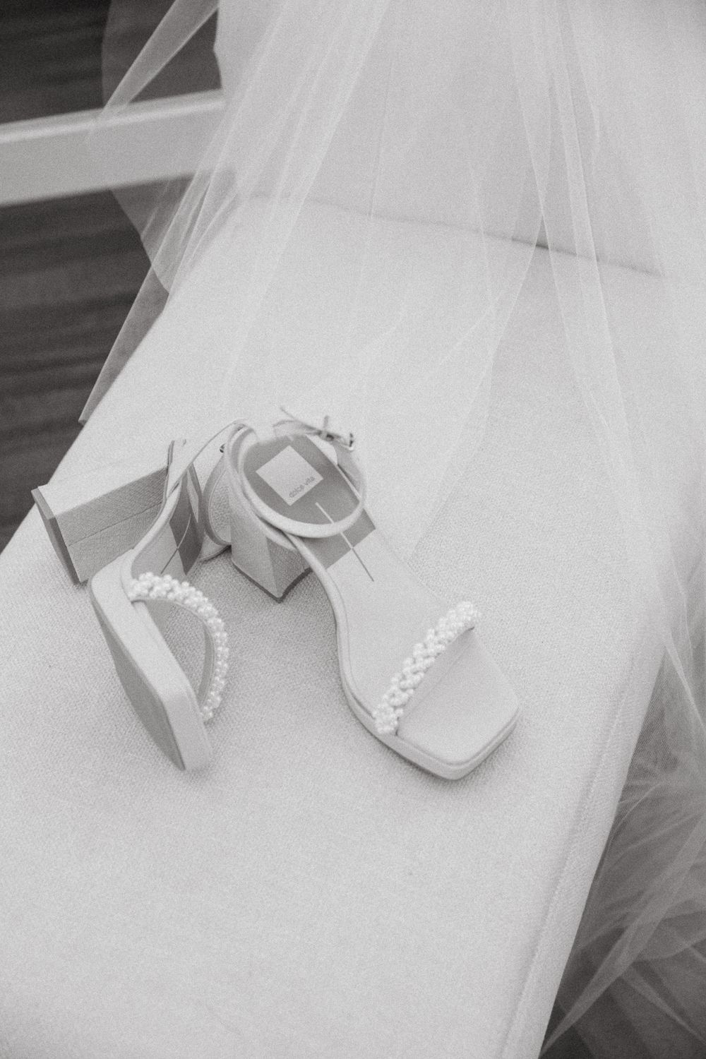 Bridal shoes and veil arranged on a light surface in black and white.