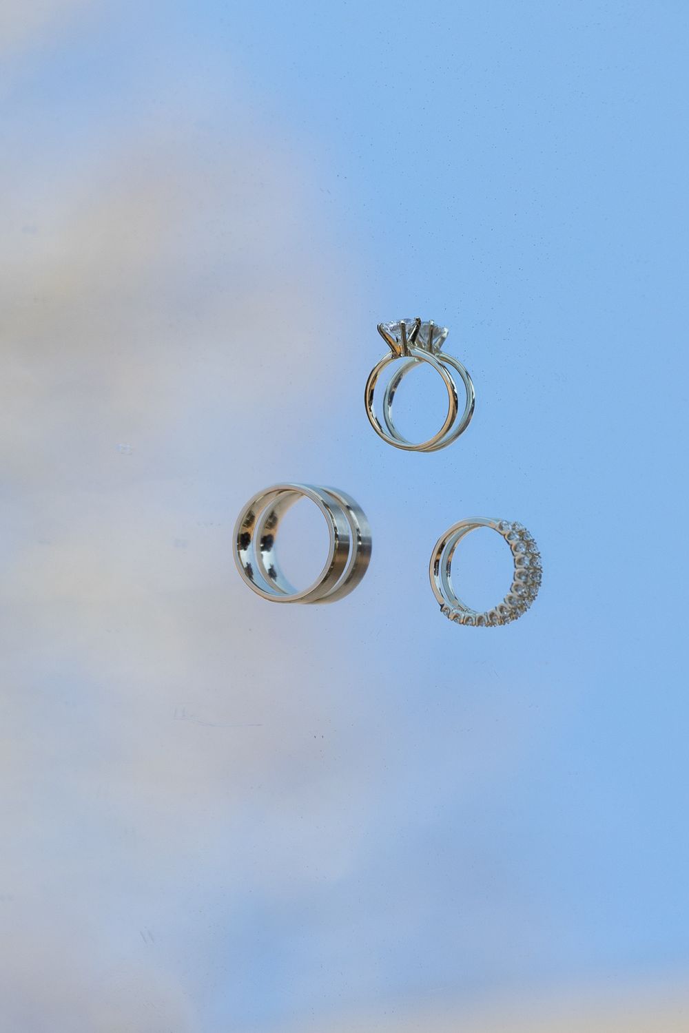 Wedding rings photographed against a bright blue sky background.