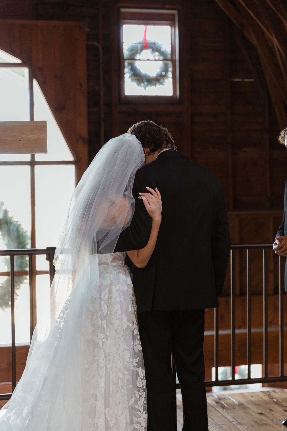 Silhouetted couple sharing an intimate moment during their first look in a rustic wooden venue.