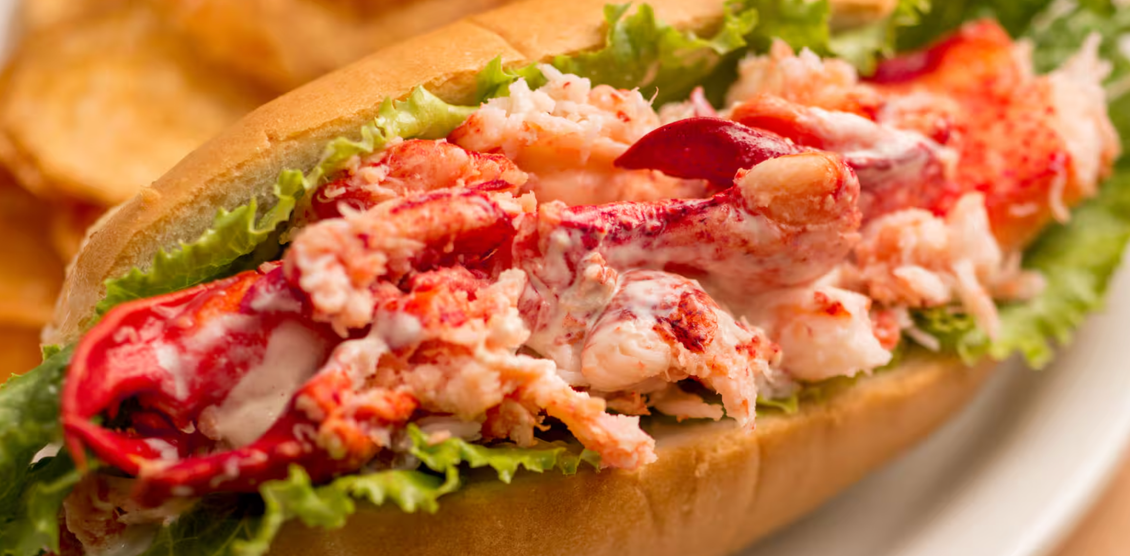 A close-up view of lobster rolls garnished with fresh lettuce and red sauce on toasted buns.