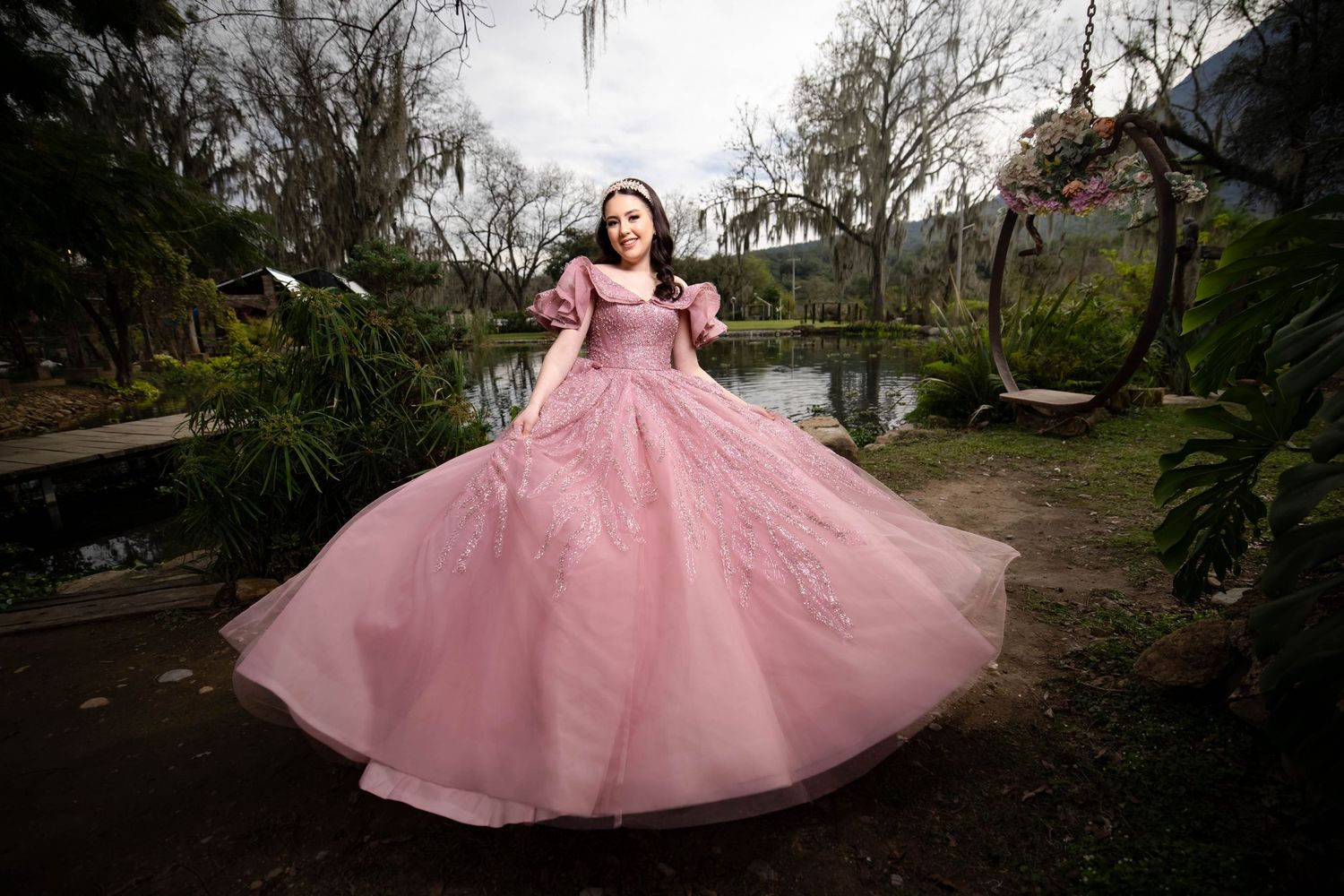 A person twirling in a pink princess ball gown in a garden setting.