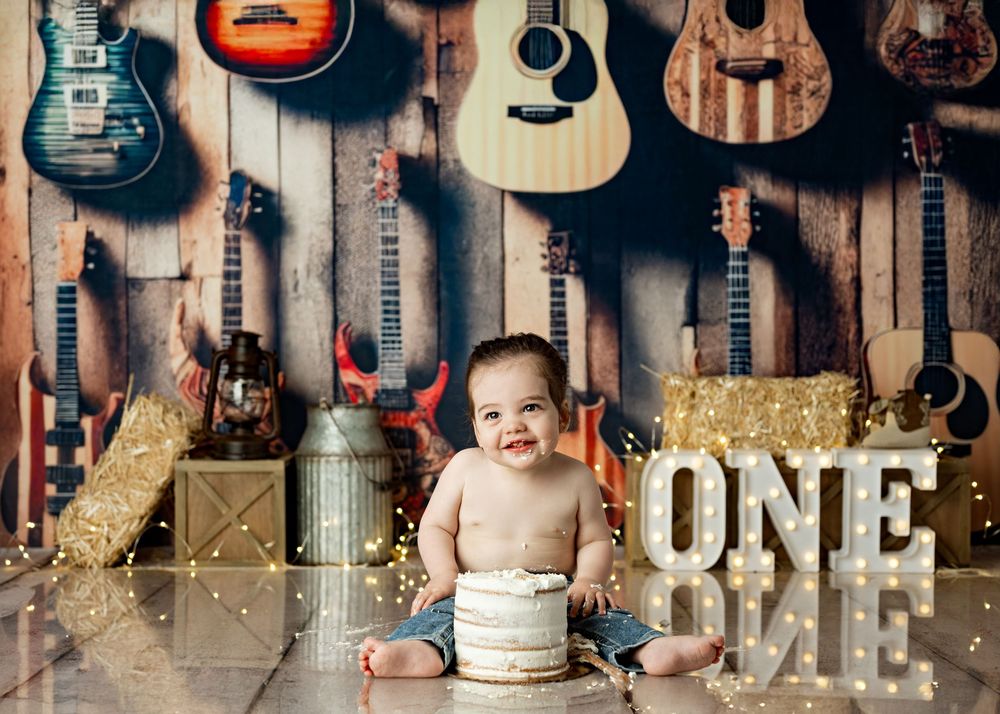 Multiple acoustic and electric guitars displayed on wooden wall with vintage finish and warm lighting.
