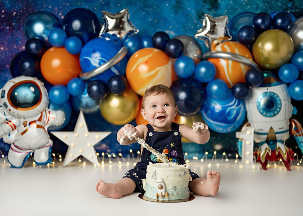 Baby's first birthday cake smash with space theme, astronaut decorations, colorful balloons, and galaxy backdrop.