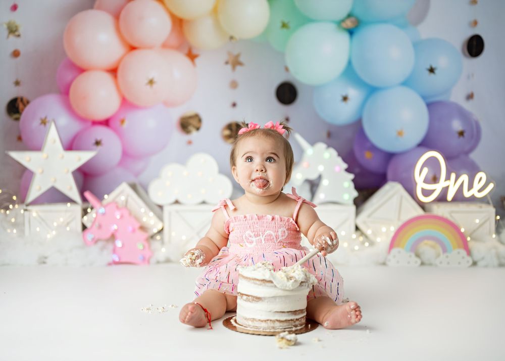 A pastel balloon arch with scattered gold stars decorates a party space against a gray wall.