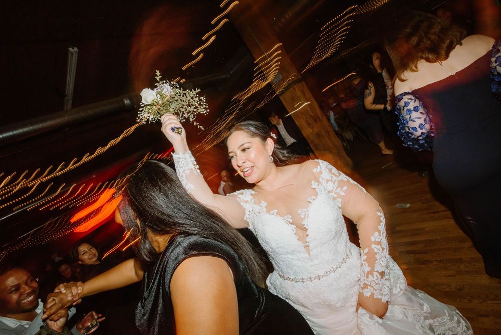 Wedding guests dancing and celebrating during reception party with bride holding her bouquet. Candid Chicago wedding photos