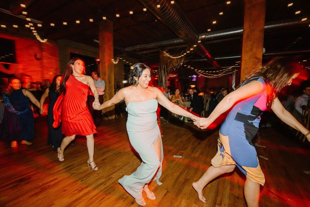Wedding guests in red and blue dresses dance with the bride. Capturing Mexican traditions at Chicago weddings.