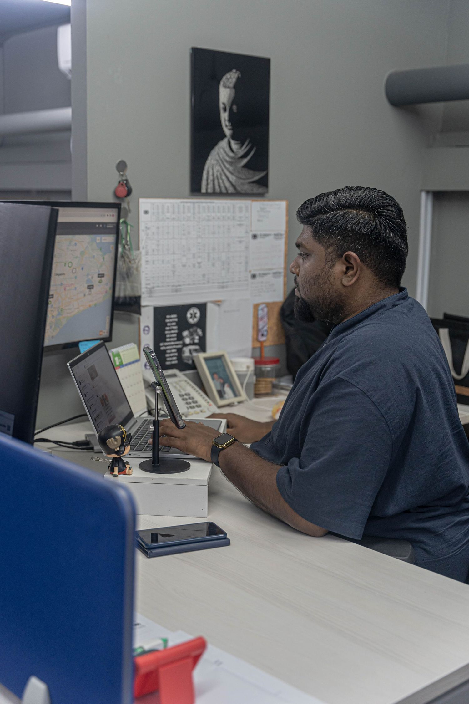A professional working at a desk setup with multiple monitors and office equipment.