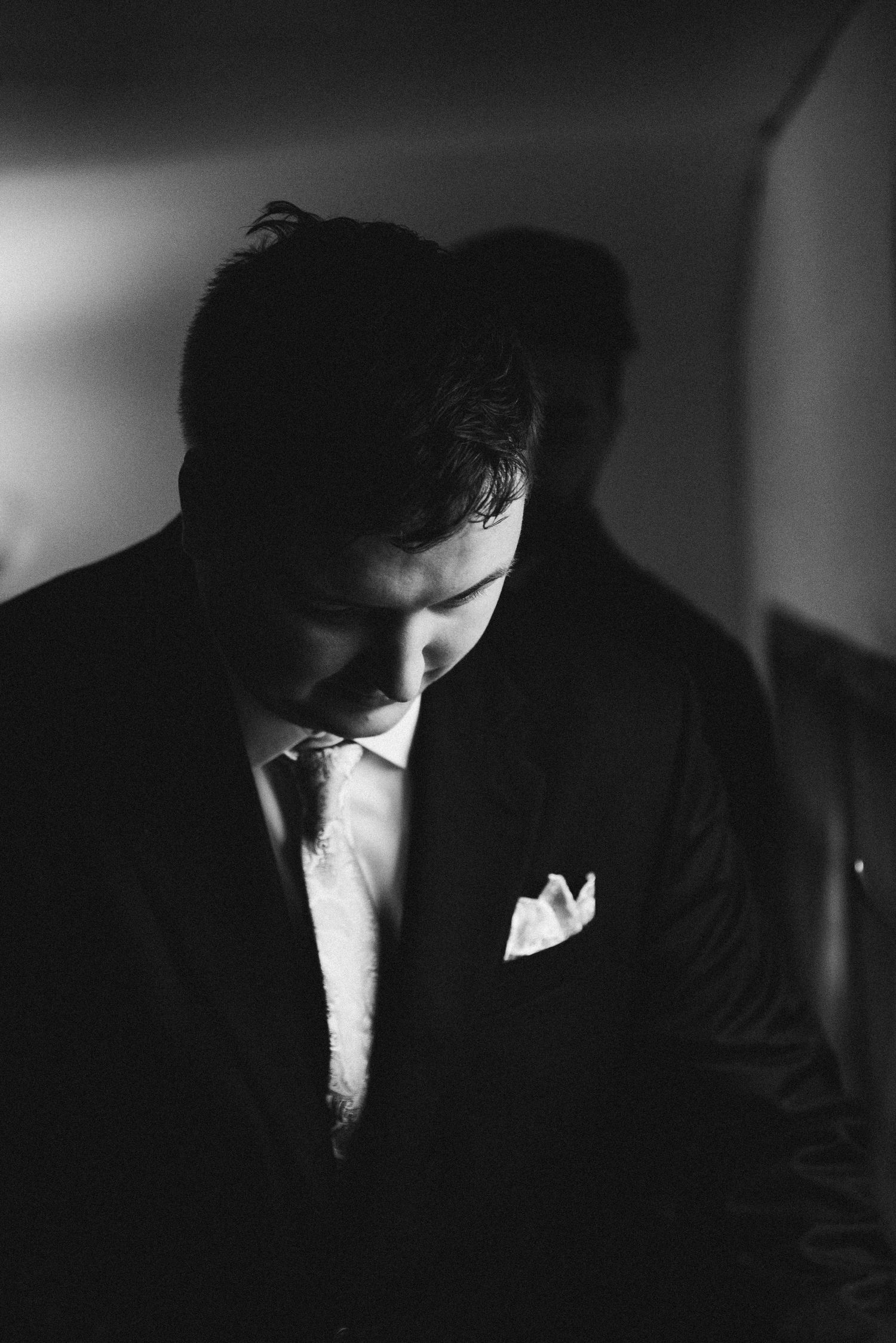 A close up black and white photo of the groom nervously getting ready before the ceremony begins.