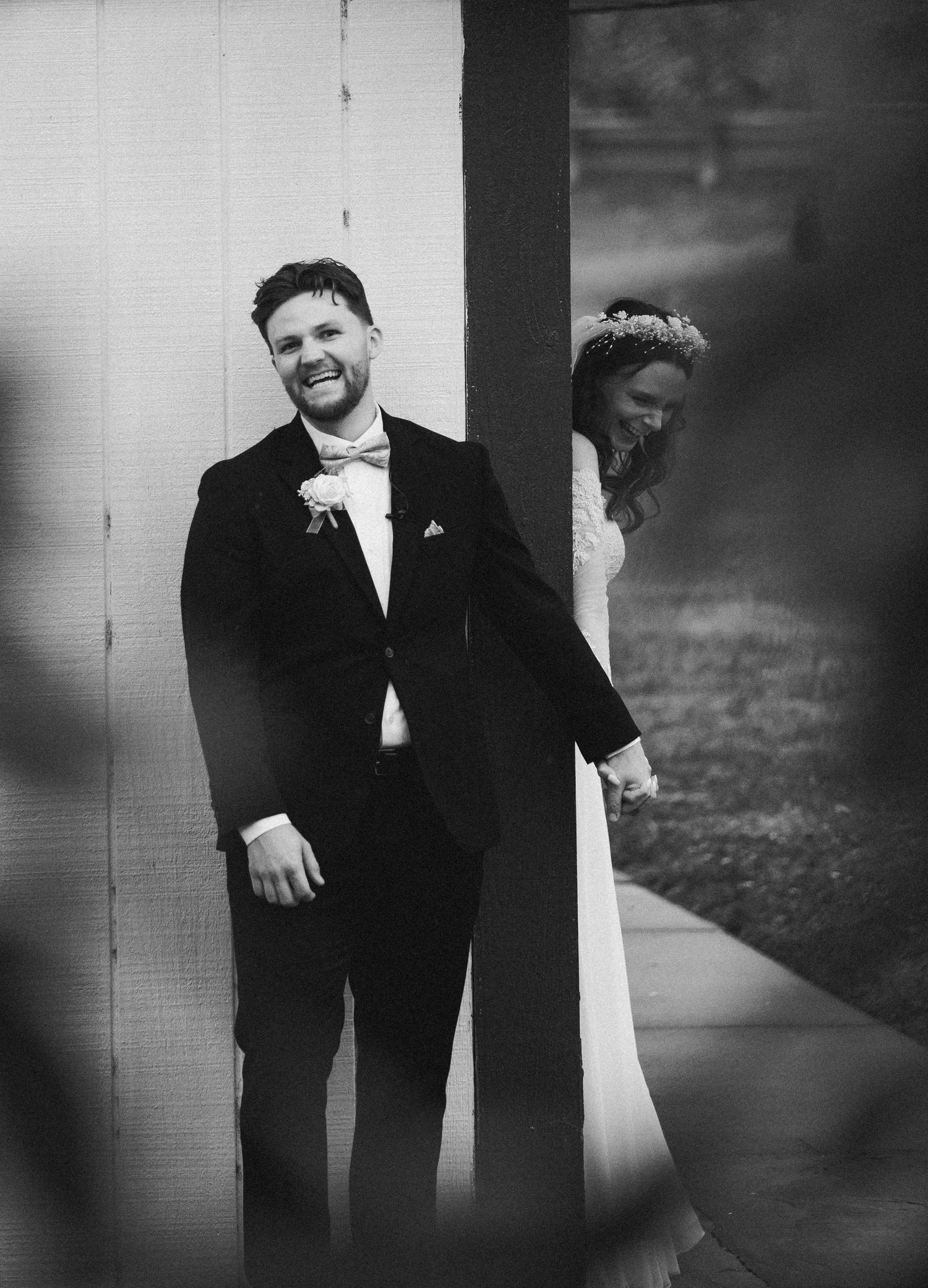 The bride and groom started laughing as they shared their "first touch" before their ceremony. The photo is in black and white.