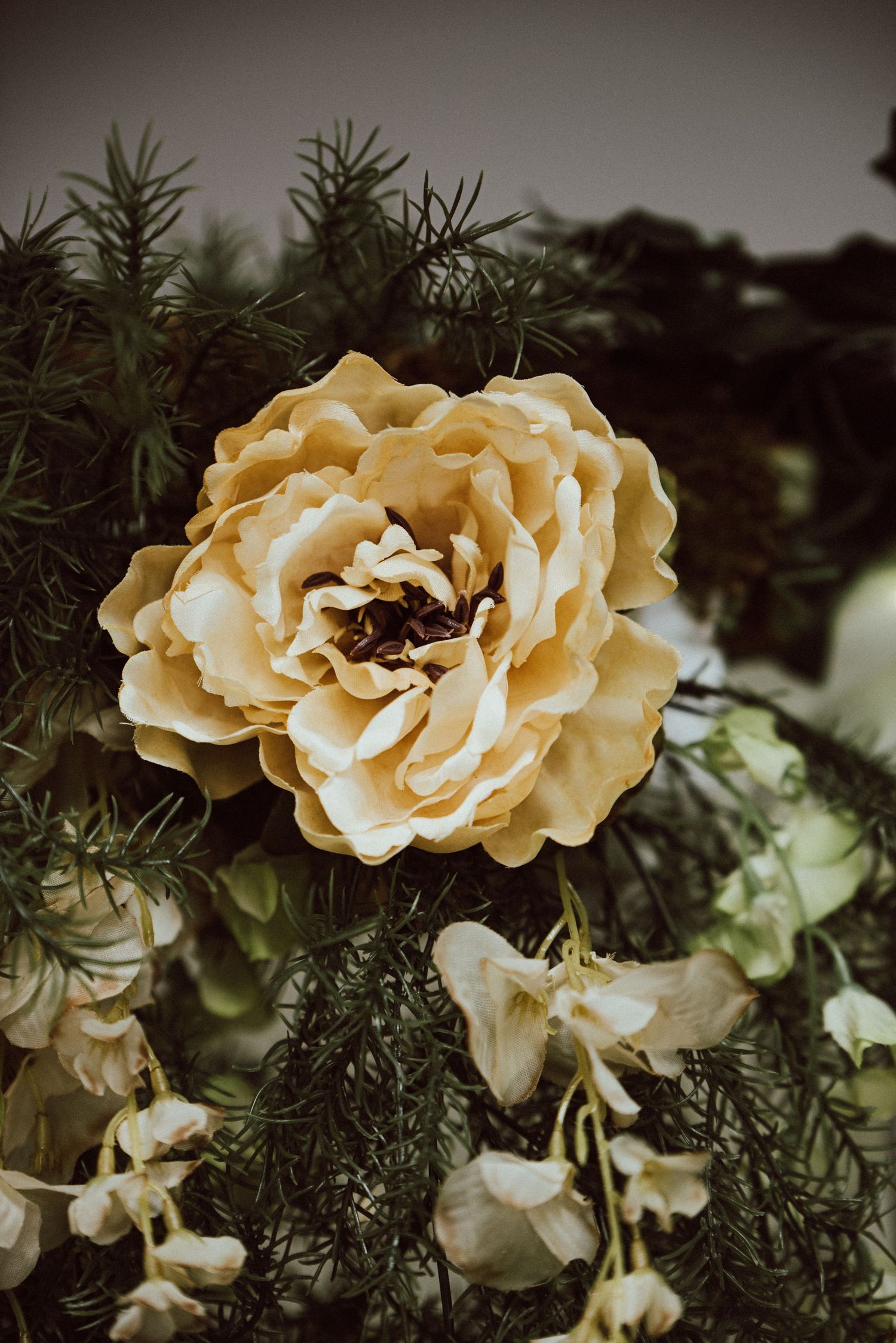 A closeup centered around an off-white rose in the bride's whimsical bouquet filled with greenery.