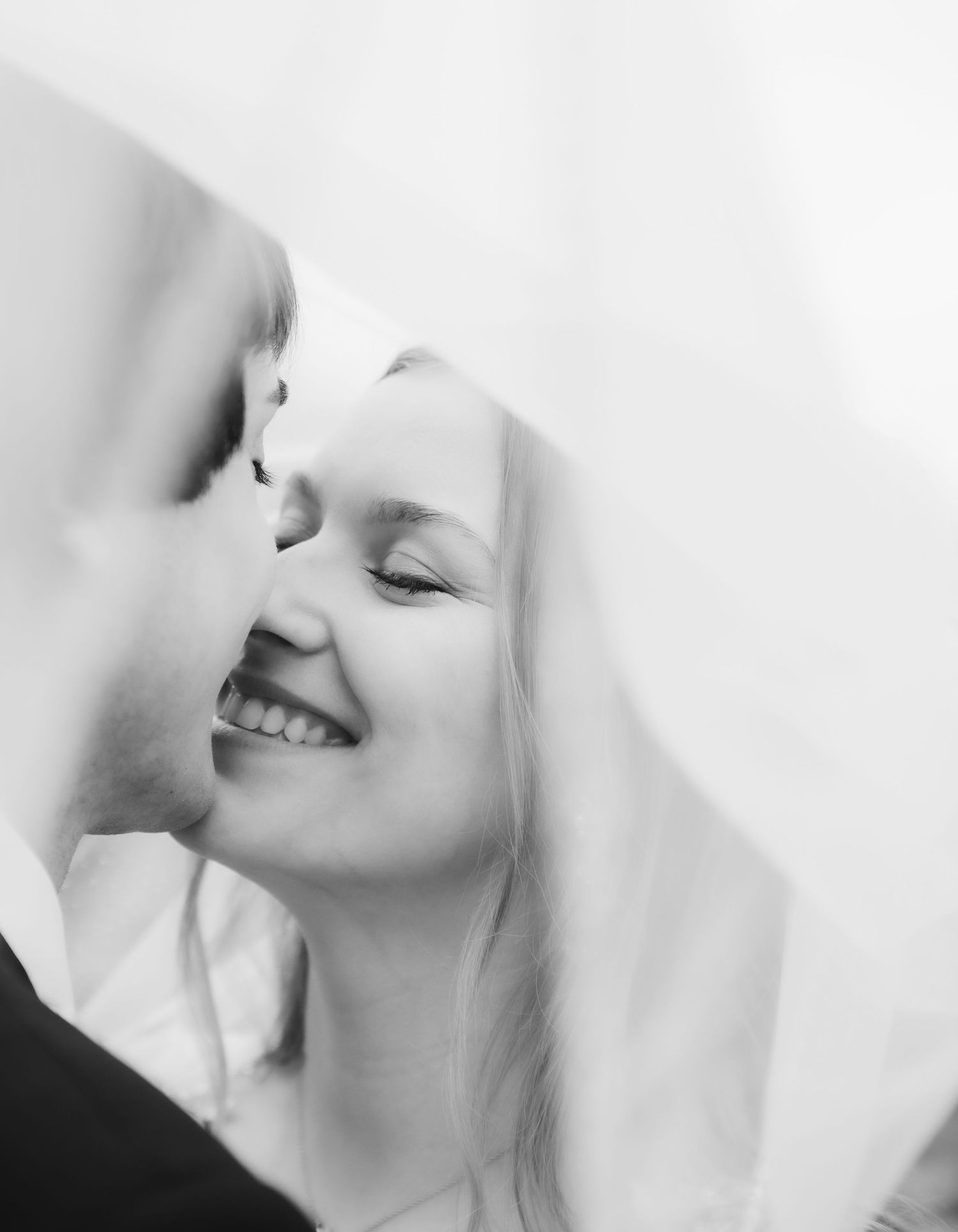Mr. and Mrs. McDuffee smile as they prepare to share a kiss under the bride's veil. The photo is in black and white.