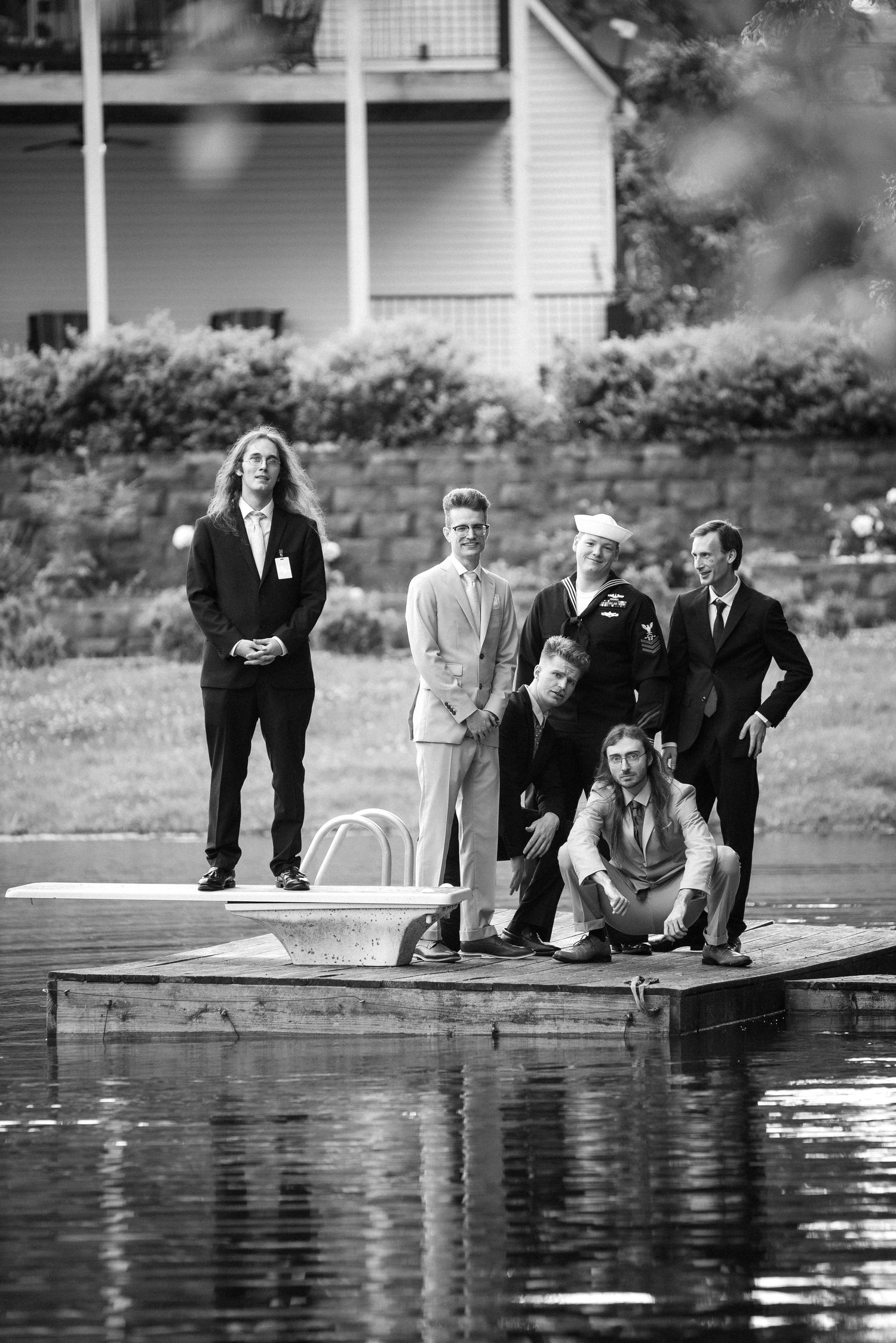 Myles and his groomsmen pose on a dock together. The photo is in black and white.