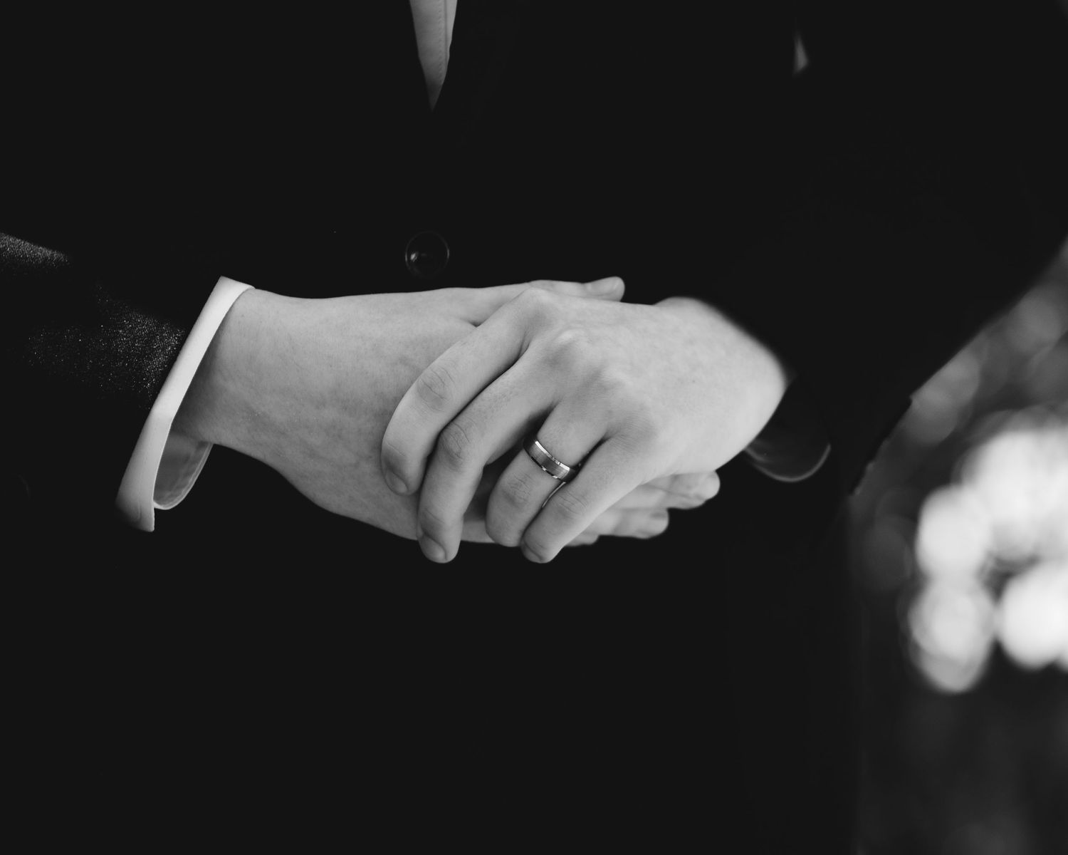 A black and white closeup of the groom fiddling with his hands before the ceremony.