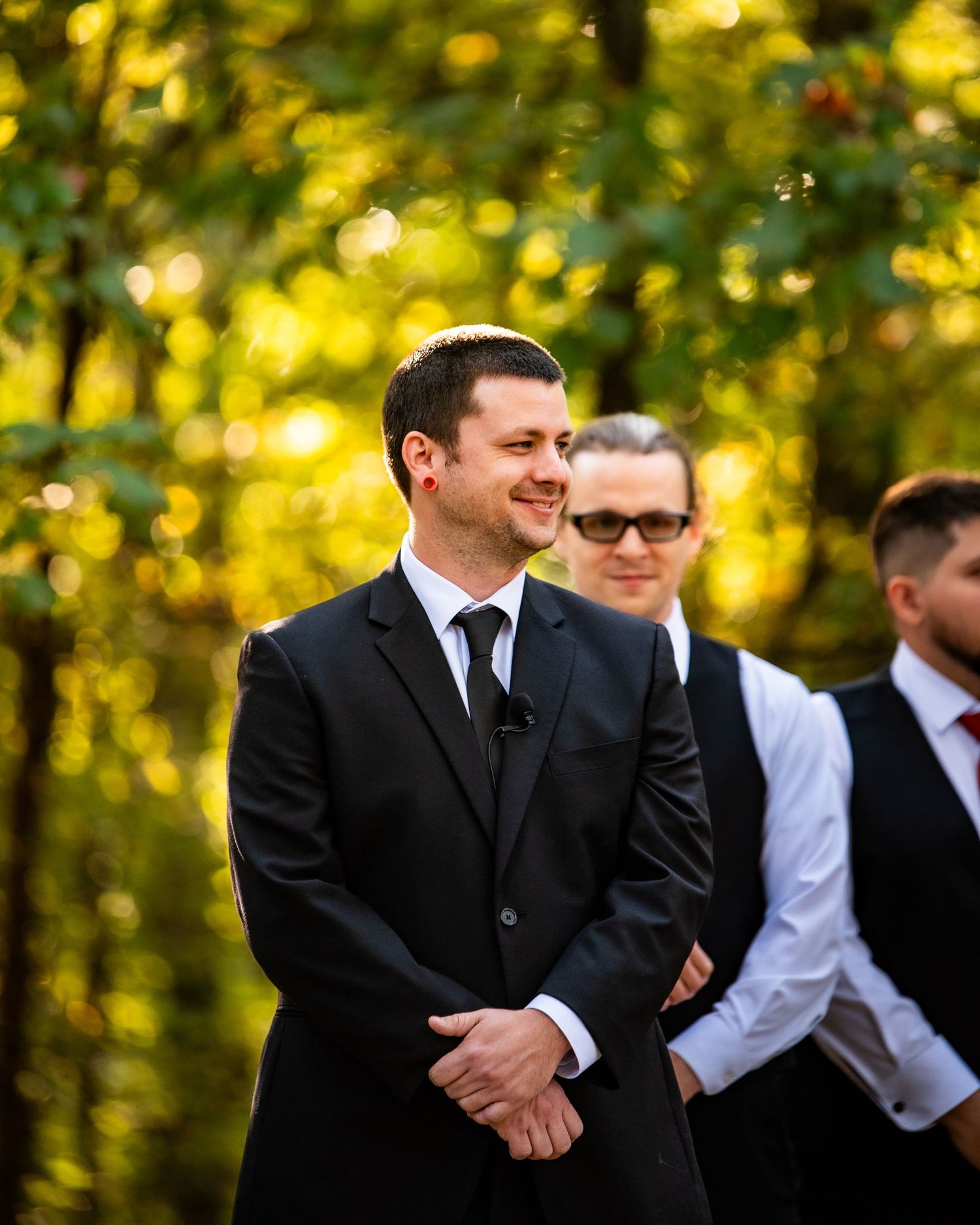 The groom smiles and looks down the aisle as he excitedly awaits his bride and soon-to-be-wife.