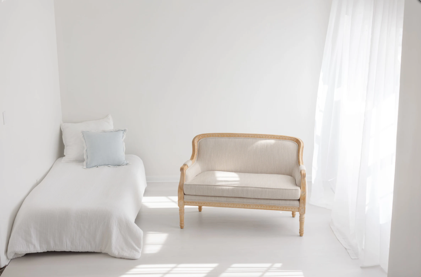 Minimalist white room interior with wooden bench and single bed.