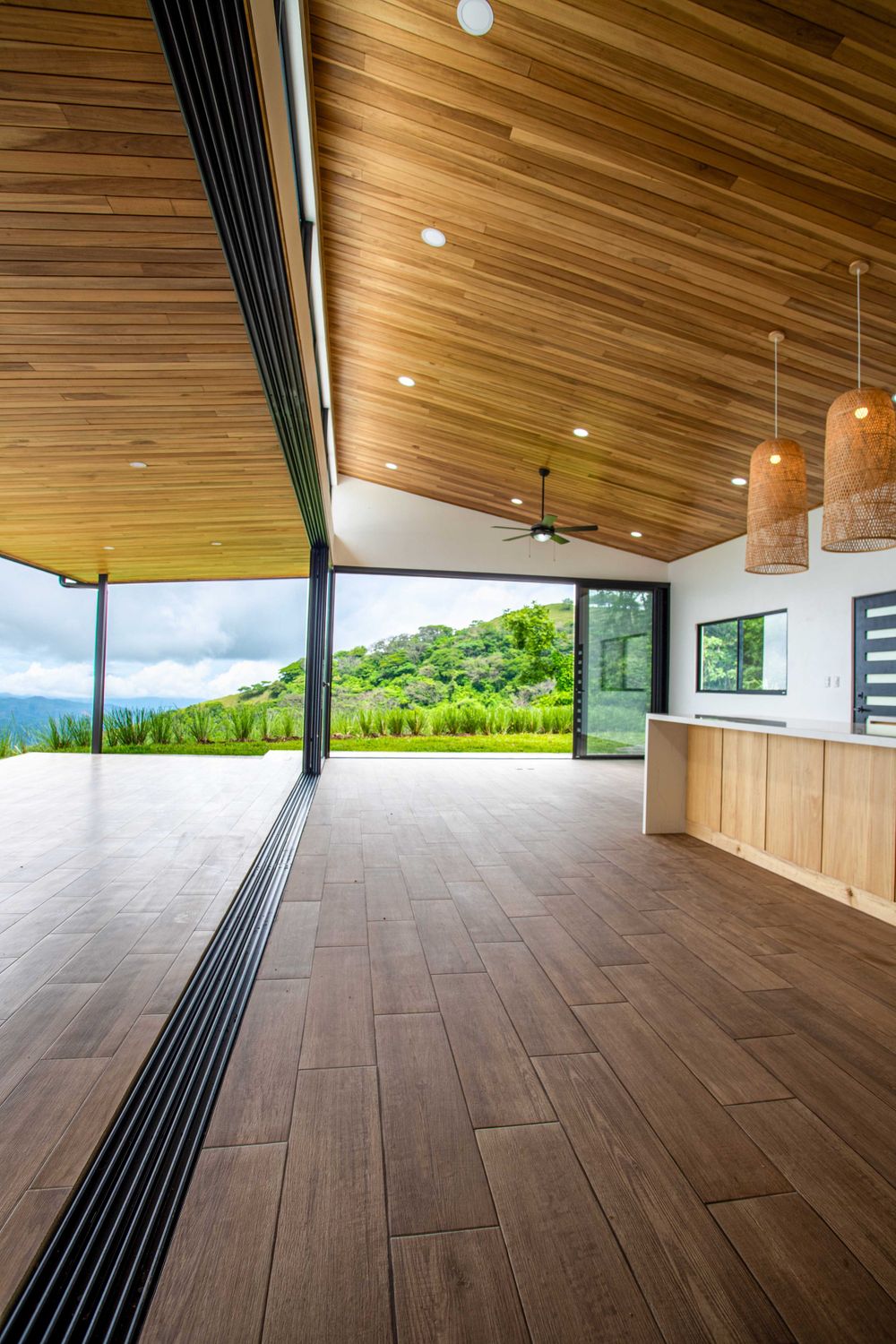 Large kitchen with wooden ceiling and large windows offering panoramic views, located in a modern property in Atenas, Costa Rica.