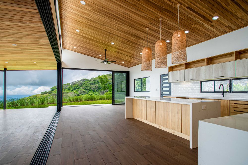 Spacious interior with wooden ceiling and large windows offering panoramic views, located in a modern property in Atenas, Costa Rica.