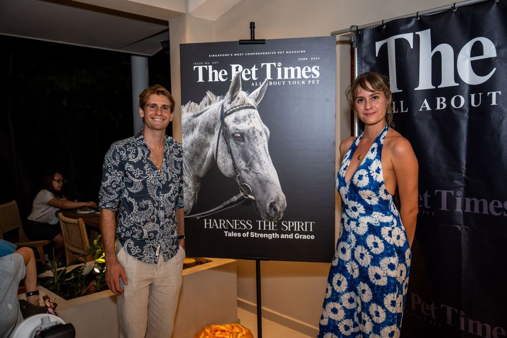Two people stand in front of The Pet Times event display banners featuring a horse portrait at an indoor venue.