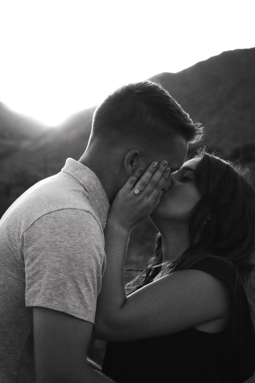 Romantic black and white photo of couple sharing intimate moment in mountain setting.