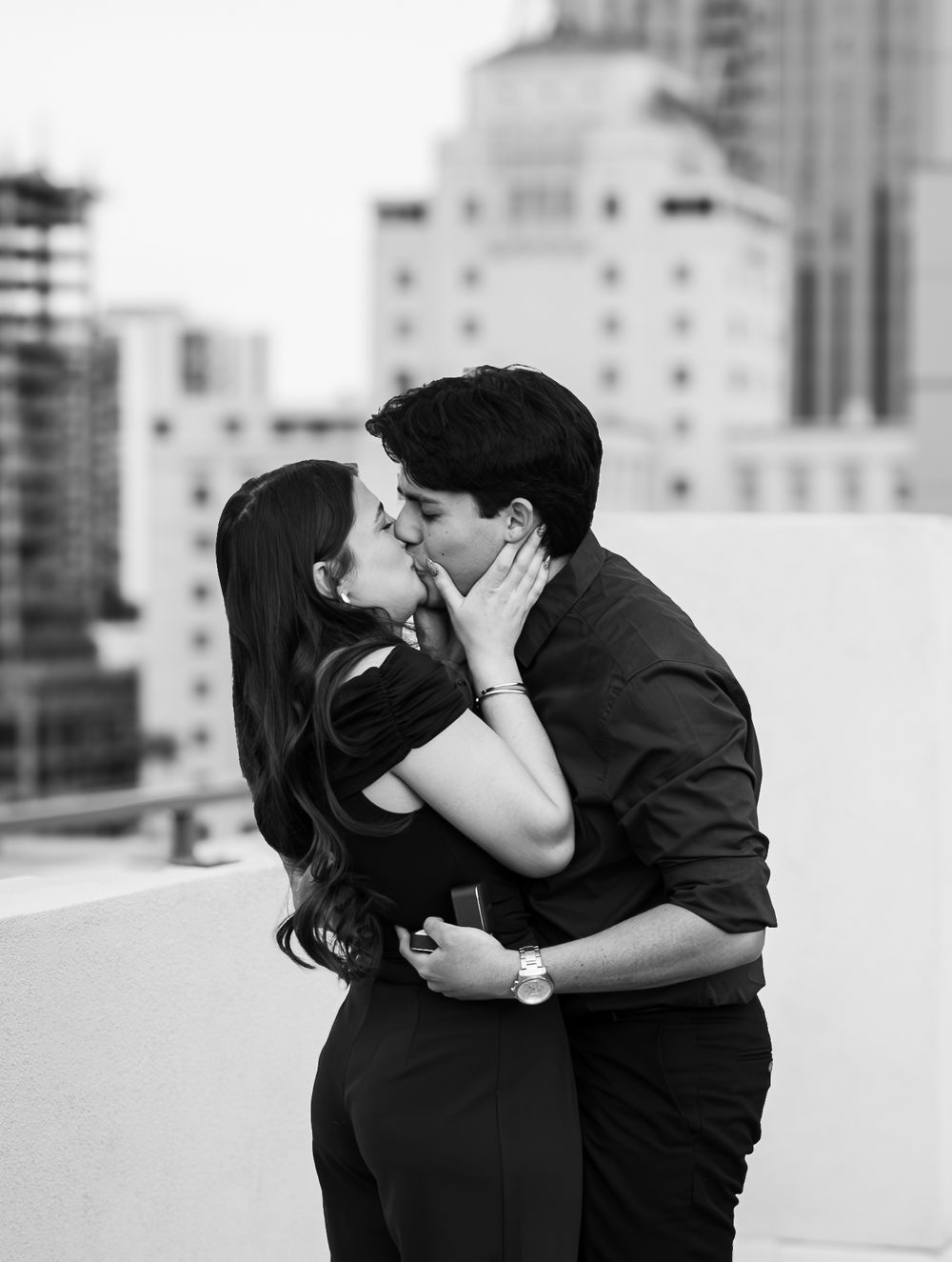 Romantic black and white portrait of couple embracing on a rooftop.