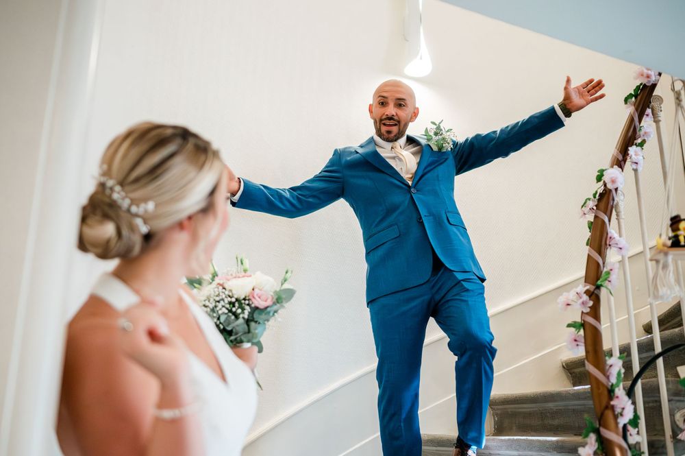 groom is very exited after the wedding and coming down a spiral staircase with the arms spread wide open at the Etat civil Chêne-Bougeries