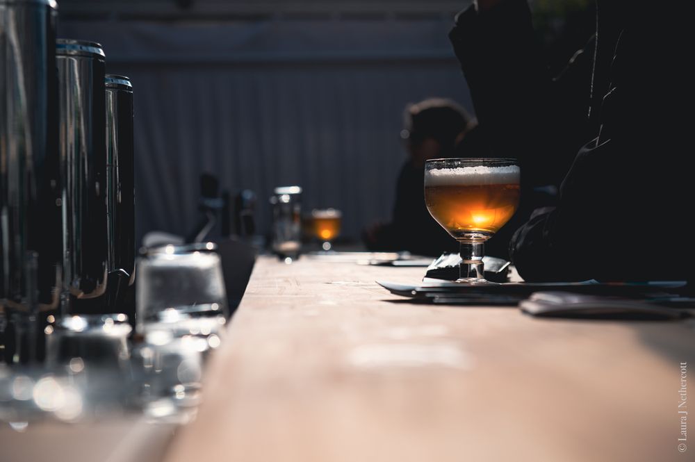 Dark bar setting with glowing amber drinks on counter in low-key lighting.