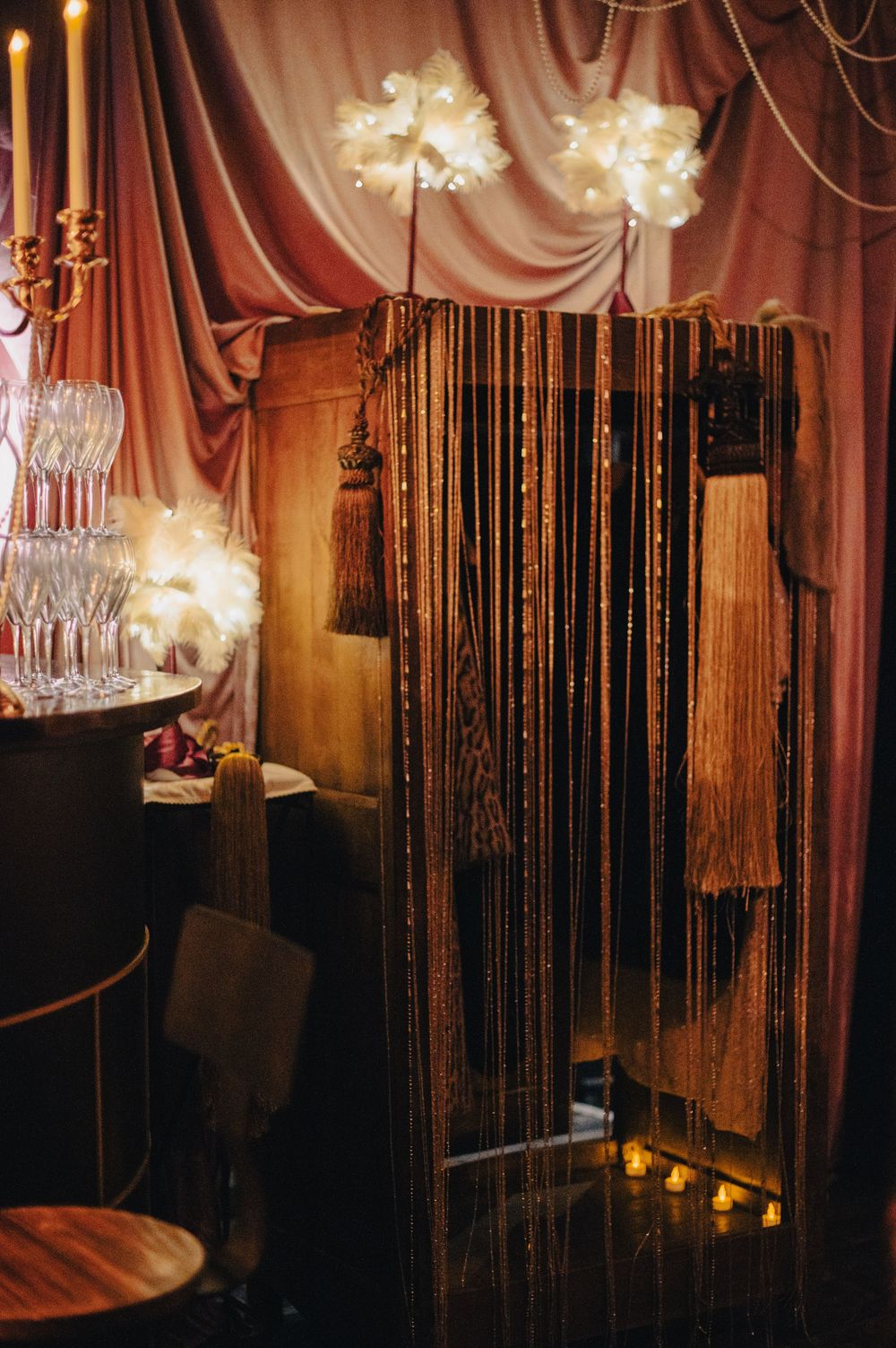 Luxurious event space decorated with draped curtains, chandeliers, and string lights creating a romantic atmosphere.