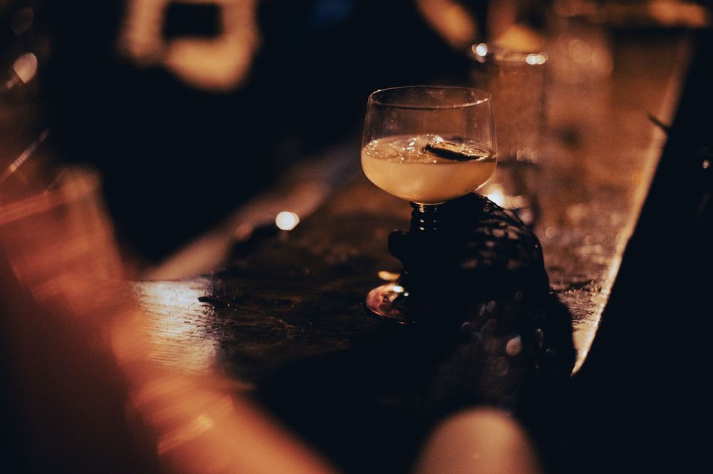 Dark and moody bar scene with glasses and bottles illuminated by soft lighting.