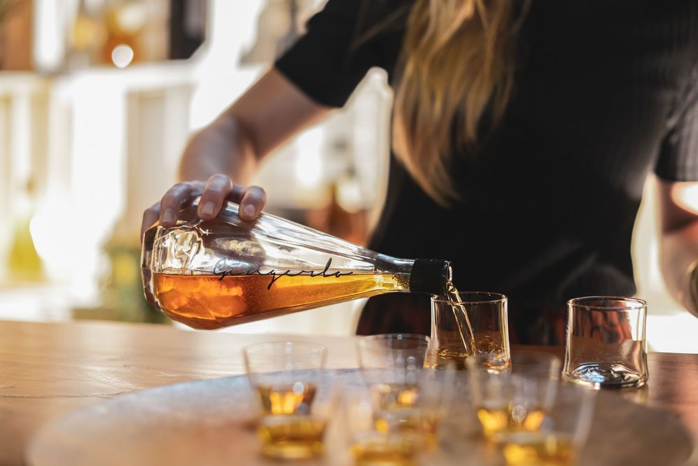 Bartenders preparing drinks at a wooden bar counter in warm lighting.