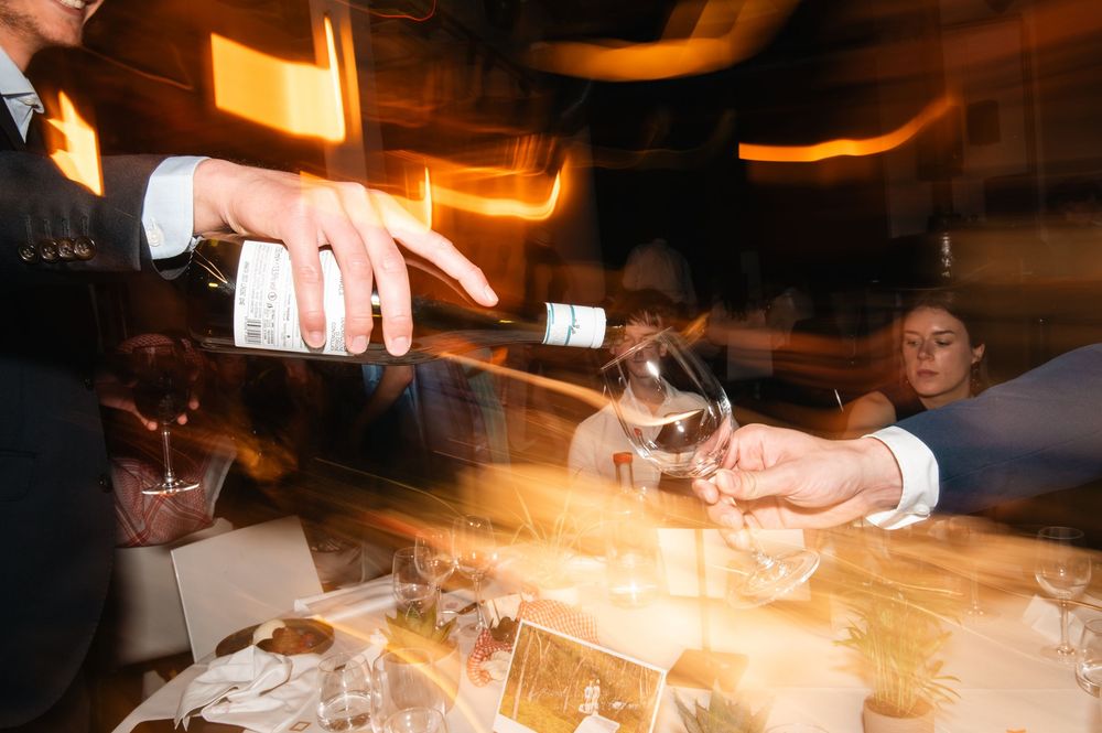 Hands reaching across a bar counter with drinks and ambient lighting.
